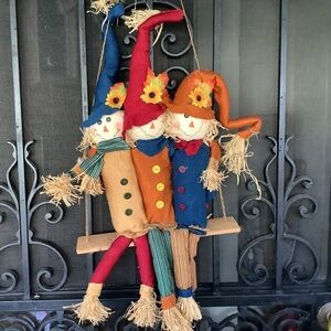 Red yellow blue hat scarecrows sitting on wood swing door window Fall Autumn dec